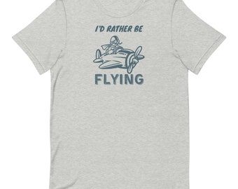 May include: A heather grey t-shirt with a blue graphic of a cartoon pilot flying a plane. The text "I'd rather be flying" is printed on the shirt.