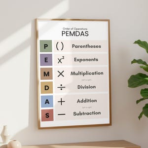 May include: A framed educational poster displaying the order of operations, PEMDAS, with colorful blocks for each step: Parentheses, Exponents, Multiplication, Division, Addition, and Subtraction. The poster is in a wooden frame and is hanging on a white wall.