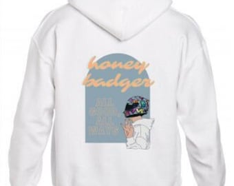 May include: White hoodie with a graphic on the back featuring the text "honey badger" in peach-colored script above a blue rectangle. Below the text is a drawing of a helmet and the words "ALL GOOD, ALL WAYS."