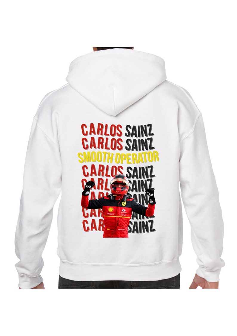 May include: White hooded sweatshirt with a red, black, and yellow graphic print of a race car driver with the text "CARLOS SAINZ" repeated multiple times and "SMOOTH OPERATOR" in between.
