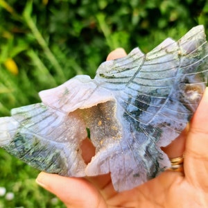 May include: A carved green and purple agate butterfly with a hollow center. The butterfly is carved with intricate details and has a natural, organic look.