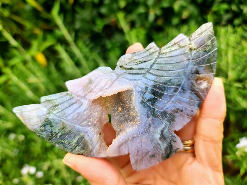 May include: A carved green and purple agate butterfly with a hollow center. The butterfly is carved with intricate details and has a natural, organic look.