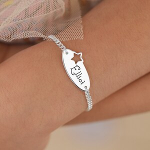 Peut inclure: Bracelet en chaîne de curb argent avec un charme ovale qui dit "Elliot" et a une étoile découpée.