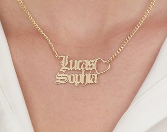 May include: Gold necklace with a heart charm and two names, "Lucas" and "Sophia", written in a gothic font.