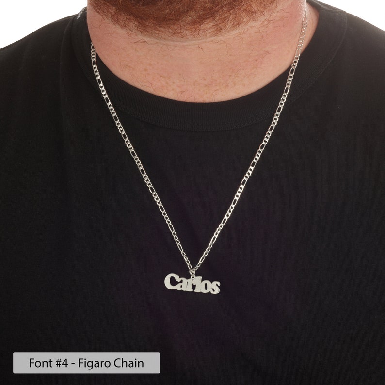 Puede incluir: Un collar de cadena Figaro plateado con un colgante plateado que dice "Carlos" en una fuente en negrita.