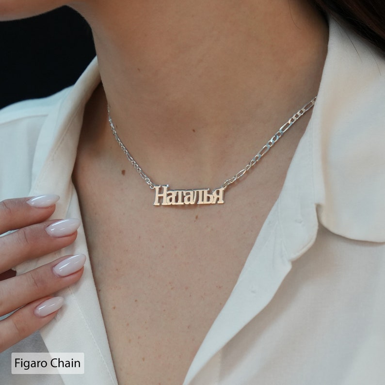 May include: A silver necklace with a Figaro chain and a nameplate pendant that reads "Наталя".