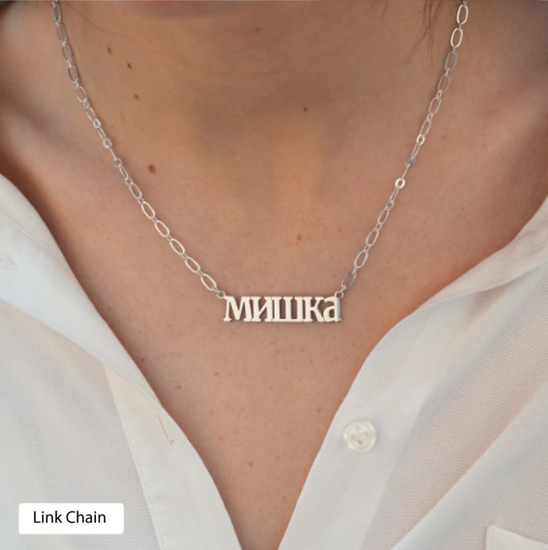 May include: A silver chain necklace with a nameplate pendant that reads "МИШКА". The chain is a link chain style.