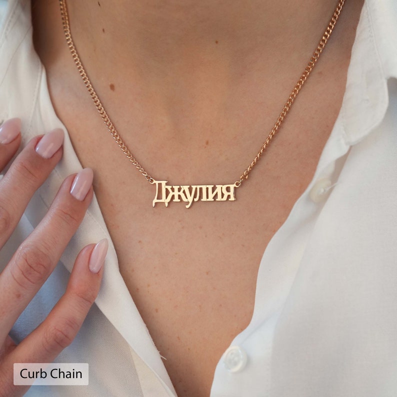 May include: A gold curb chain necklace with a personalized nameplate pendant that reads "Джулия".