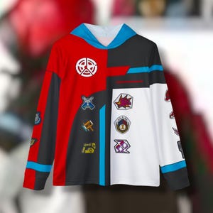 Może przedstawiać: Czarny, czerwony i biały longsleeve z kapturem w kolorze niebieskim. Bluza ma różne kolorowe naszywki z przodu, w tym gwiazdę, koło i kwadrat.