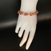 May include: A copper bracelet with a woven knot design.