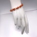 May include: A rose gold chain bracelet with a woven knot design.