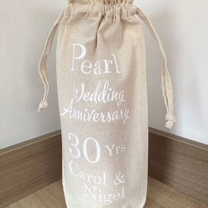 May include: A white cotton drawstring bag with the text "Pearl Wedding Anniversary 30 Yrs Carol & Nigel" printed on it.