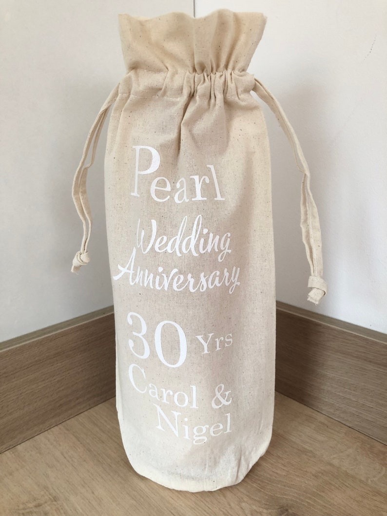 May include: A white cotton drawstring bag with the text "Pearl Wedding Anniversary 30 Yrs Carol & Nigel" printed on it.