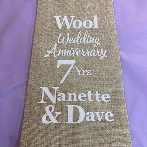 May include: A brown burlap bag with a white drawstring. The bag has white text that reads "Wool Wedding Anniversary 7 Yrs Nanette & Dave".