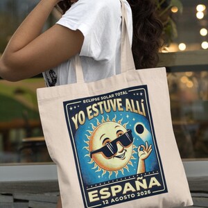 Op de afbeelding: Crèmekleurige draagtas met een retro-stijl afbeelding van een lachende zon met zonnebril, met de tekst "YO ESTUVE ALLI" en "ESPAÑA 12 AGOSTO 2026". Het ontwerp staat tegen een blauwe achtergrond.