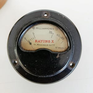 Könnte beinhalten: Eine weiße Keramik-Tasse mit schwarzem Henkel und dem Text "But First, Coffee" in fetter, schwarzer Schrift. Die Tasse steht auf einer Holzoberfläche. Die Tasse ist etwa 10 cm hoch.