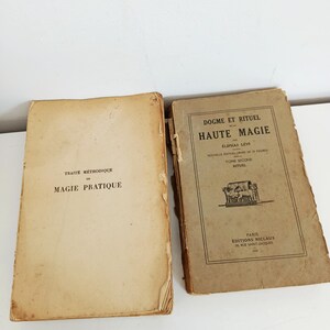 May include: Two antique books with aged, tan covers. The left book reads "TRAIT&Eacute; M&Eacute;THODIQUE DE MAGIE PRATIQUE." The right book is titled "DOGME ET RITUEL DE HAUTE MAGIE" by &Eacute;liphas L&eacute;vi. Both books show signs of wear.