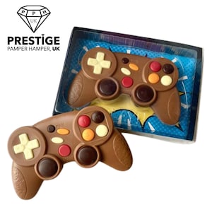 May include: Two chocolate game controllers, one in a clear plastic box with a blue and yellow comic book style background. The controllers are brown with colourful buttons.