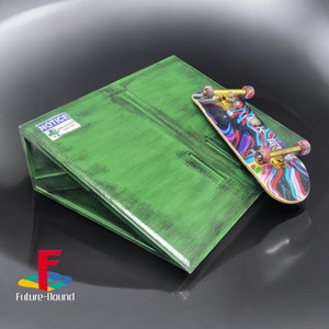 Puede incluir: Una rampa verde con un letrero de "NOTICE EMERGENCY SHELTER" y una tabla de skate de dedo colorida en la parte superior.