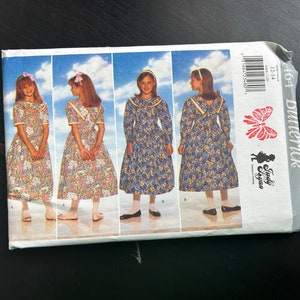 May include: A sewing pattern for a dress with a sailor collar. The pattern is for sizes 12-14 and is from Simplicity. The pattern shows a girl wearing the dress in four different poses.