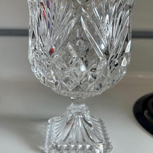 May include: A clear glass bowl with a cut crystal design. The bowl sits on a square pedestal base.