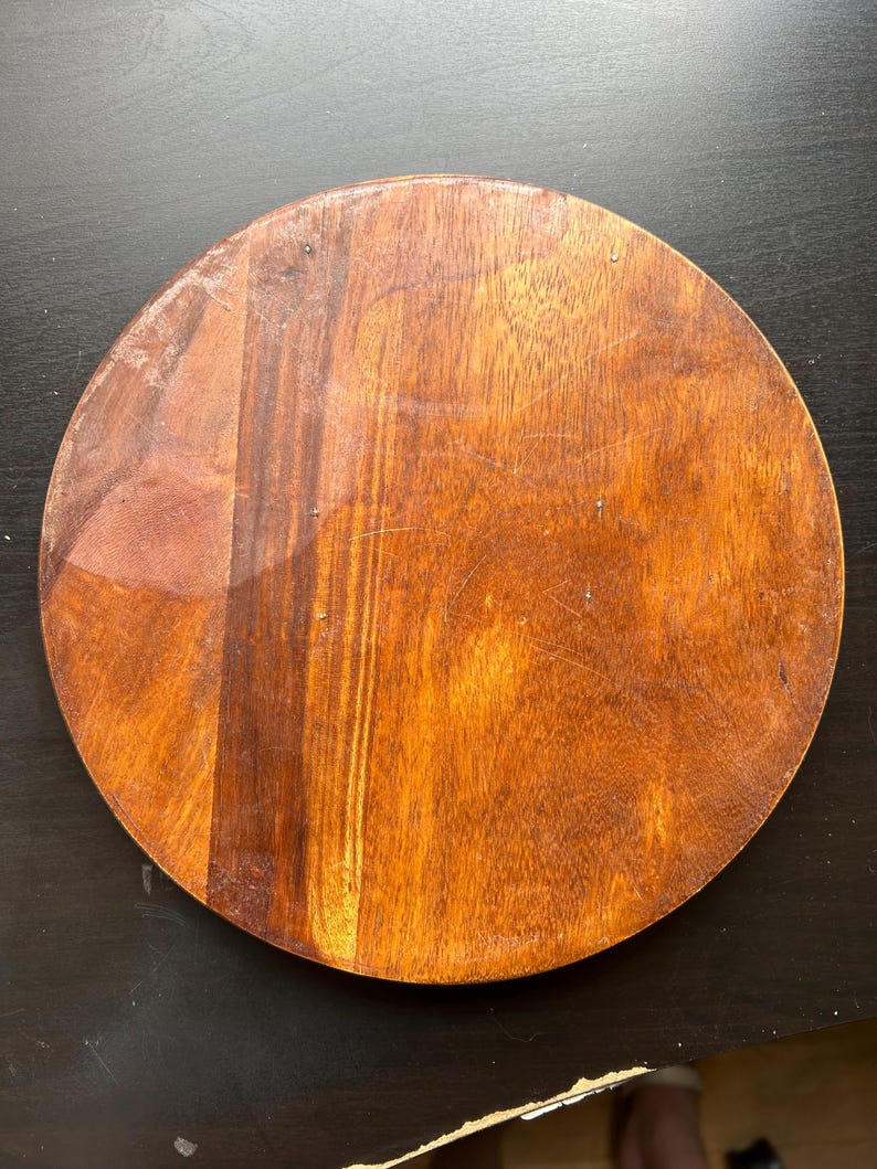 May include: A round wooden cutting board with a natural brown finish. The board has a smooth surface and is perfect for chopping vegetables or serving cheese.