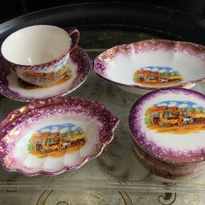 Könnte beinhalten: Ein Set aus vier antiken Porzellantellern mit violetten und goldenen Akzenten. Jeder Teller zeigt eine andere Szene mit einer Pferdekutsche und dem Text "Dorking Downs".