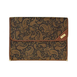 May include: A rectangular brown and black paisley patterned portfolio with a flap closure. The portfolio has a brown leather trim and a small rectangular label with the text "PIERRE BALMAIN".