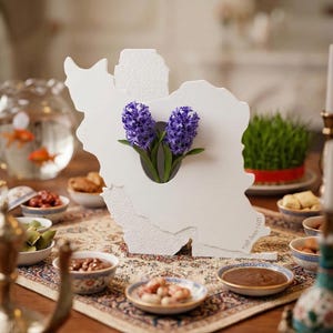 May include: A white paper cutout in the shape of Iran, with purple hyacinth flowers. The table is set with small bowls of food, a fishbowl with goldfish, and a decorative rug.