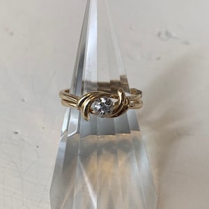 May include: A gold ring with a single round diamond set in a twisted band.