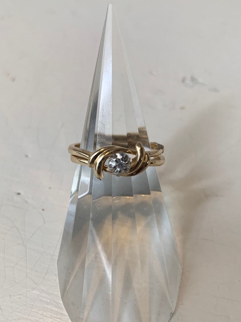 May include: A gold ring with a single round diamond set in a twisted band.