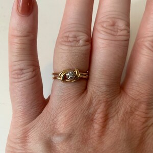 May include: A gold ring with a knot design and a small diamond in the center.