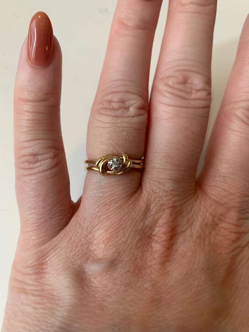May include: A gold ring with a knot design and a small diamond in the center.