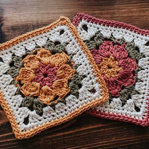 K&ouml;nnte beinhalten: Zwei quadratische H&auml;keluntersetzer mit Blumendesigns. Ein Untersetzer zeigt eine Blume in Orange- und Rosat&ouml;nen mit gr&uuml;nen Bl&auml;ttern und einem cremefarbenen Hintergrund. Der andere Untersetzer hat ein &auml;hnliches Design, aber mit rosa Rand und Blume.
