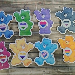 May include: Eight colorful cartoon bear stickers with different pride flag hearts. The bears are all in different poses and have different colored fur. The hearts are all different colors and have different pride flag designs.