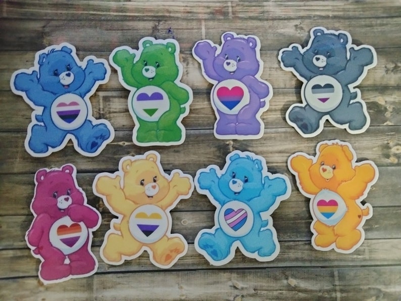 May include: Eight colorful cartoon bear stickers with different pride flag hearts. The bears are all in different poses and have different colored fur. The hearts are all different colors and have different pride flag designs.