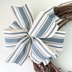 May include: A blue and white striped bow tied on a brown grapevine wreath. The bow is made of a thick, woven fabric.