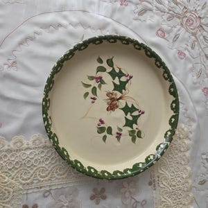 May include: A white ceramic mug with a black handle and the text "But First, Coffee" in a handwritten style. The mug is on a white surface. The mug is approximately 4 inches tall.