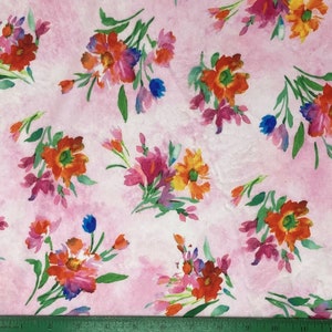 May include: A fabric with a watercolor floral pattern. The design features clusters of flowers in shades of orange, red, pink, purple, and blue, set against a soft pink background. Green leaves and stems add contrast. The fabric is suitable for various craft projects.