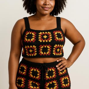 Op de afbeelding: Een zwarte gehaakte crop top en short set. De set heeft een vierkant patroon in rood en geel. De top heeft brede bandjes en de short heeft een taille met trekkoord. De outfit is handgemaakt en perfect voor de zomer.