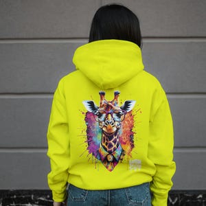 May include: A bright yellow hoodie with a colourful giraffe wearing glasses and a bow tie printed on the back. The giraffe is surrounded by colourful paint splatters.
