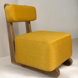 以下が含まれることがあります： 木製のフレームに黄色の布張りで覆われたロッキングチェア。正方形の座面と長方形の背もたれがあります。