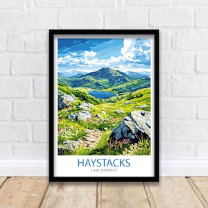 May include: A framed print depicting the Haystacks mountain range in the Lake District. The artwork shows a scenic view with a lake, green hills, and a path. The text "HAYSTACKS LAKE DISTRICT" is printed in blue at the bottom of the print.