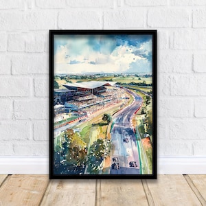 May include: Watercolor painting of a race track with grandstands and race cars. The artwork is framed in a black frame and depicts a sunny day with a blue sky and clouds. The track is surrounded by green fields and trees.