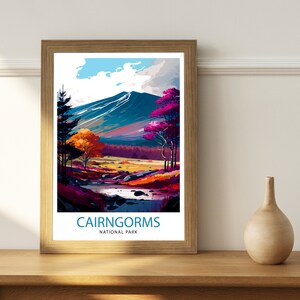 K&ouml;nnte beinhalten: Ein gerahmtes Poster mit einer farbenfrohen Illustration einer Bergkette mit einem Fluss, der durch sie flie&szlig;t. Das Poster tr&auml;gt den Text "Cairngorms National Park" am unteren Rand.