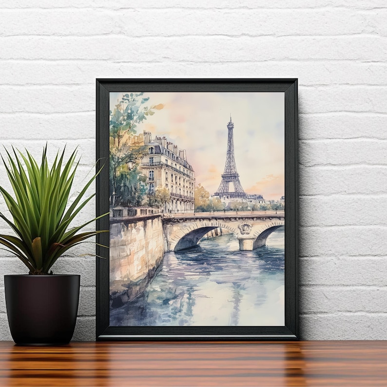 Op de afbeelding: Een aquarel schilderij van de Eiffeltoren in Parijs, Frankrijk. De schildering toont de toren in de verte, met een brug en gebouwen op de voorgrond. Het water in de rivier is lichtblauw en de lucht is lichtroze.