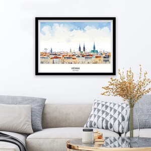 Peut inclure: Une peinture &agrave; l'aquarelle de l'horizon de Vienne, mettant en sc&egrave;ne les b&acirc;timents embl&eacute;matiques de la ville, dont la cath&eacute;drale Saint-&Eacute;tienne. La peinture est sur fond de ciel bleu avec des nuages blancs. Le texte "VIENNA, AUSTRIA" est imprim&eacute; sous l'horizon.
