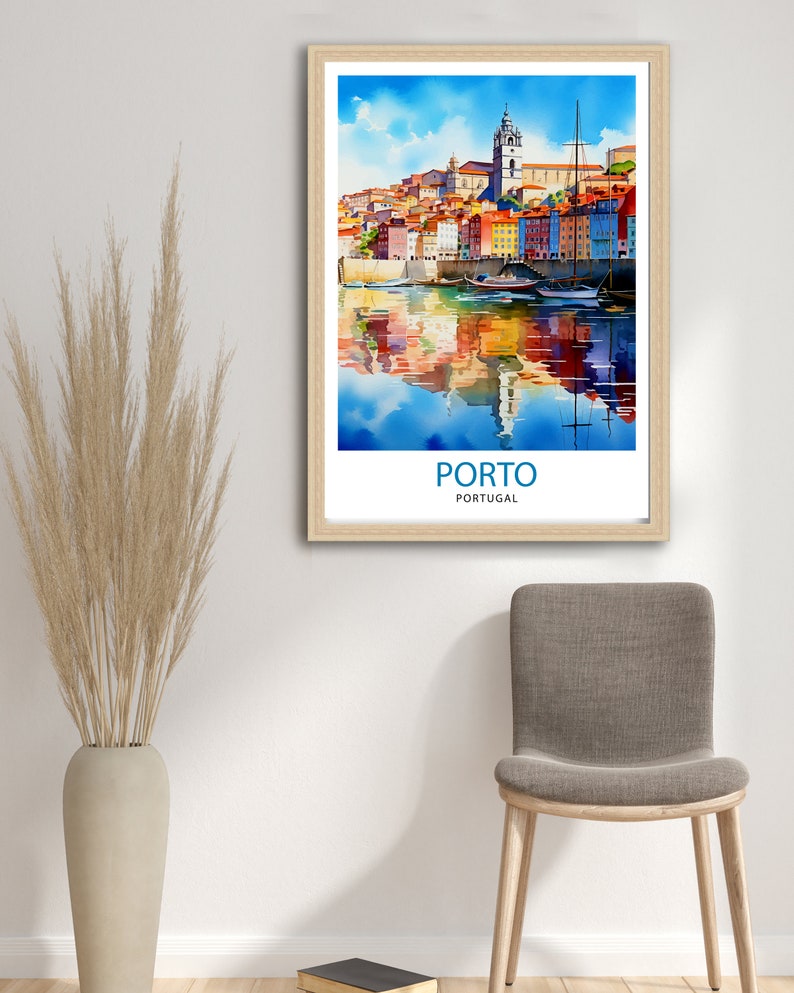 May include: A watercolor painting of the city of Porto, Portugal. The painting depicts colorful buildings along the Douro River with boats docked in the water. The painting is framed in a light wood frame.