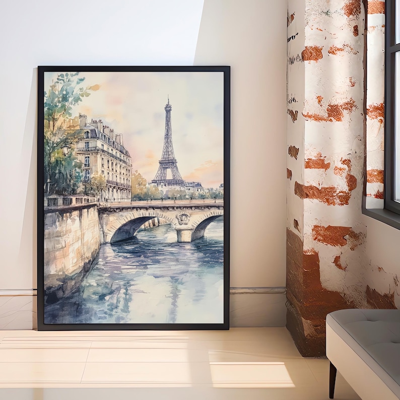 Op de afbeelding: Een aquarel schilderij van de Eiffeltoren in Parijs, Frankrijk. De schildering toont de toren vanuit de verte, met een brug op de voorgrond en gebouwen aan weerszijden van de rivier. De lucht is lichtblauw en het water is lichtblauw met reflecties van de gebouwen en de toren.