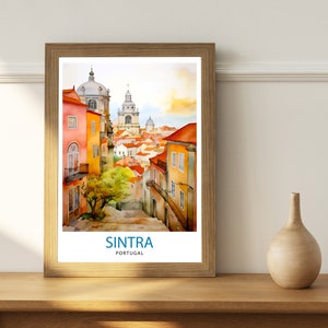 Puede incluir: Una pintura de acuarela enmarcada de una escena callejera en Sintra, Portugal. La pintura presenta una calle estrecha bordeada de edificios coloridos, un peque&ntilde;o &aacute;rbol y una vista de la ciudad en la distancia. El texto "SINTRA PORTUGAL" est&aacute; impreso en la parte inferior de la pintura.